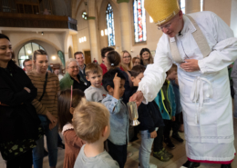 Bischöf läßt die Kinder am Chrisam-Öl riechen