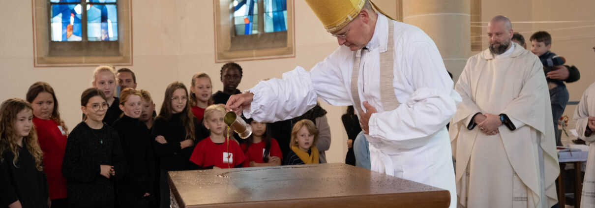 Bischof schüttet Chrisam-Öl auf den zukünftigen Altar