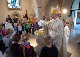 Bischof besprengt die Gemeinde mit Weihwasser nach der Tauferneuerung.